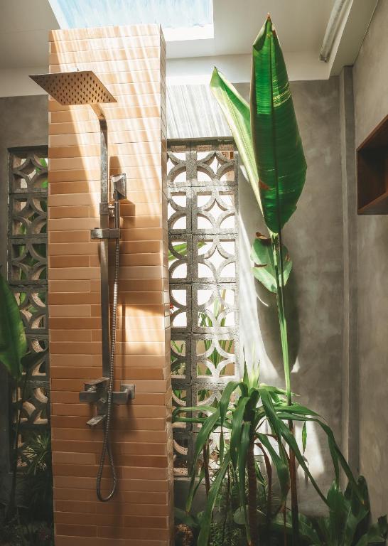 Open-air tropical shower with breeze block wall and banana leaf plant