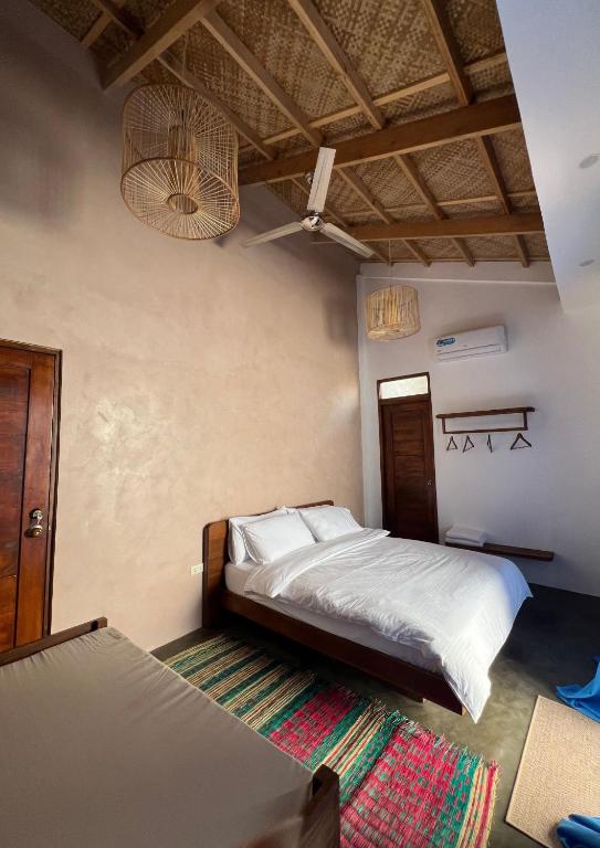 Single Fin cabana room with traditional bamboo ceiling, bed, and colorful rug